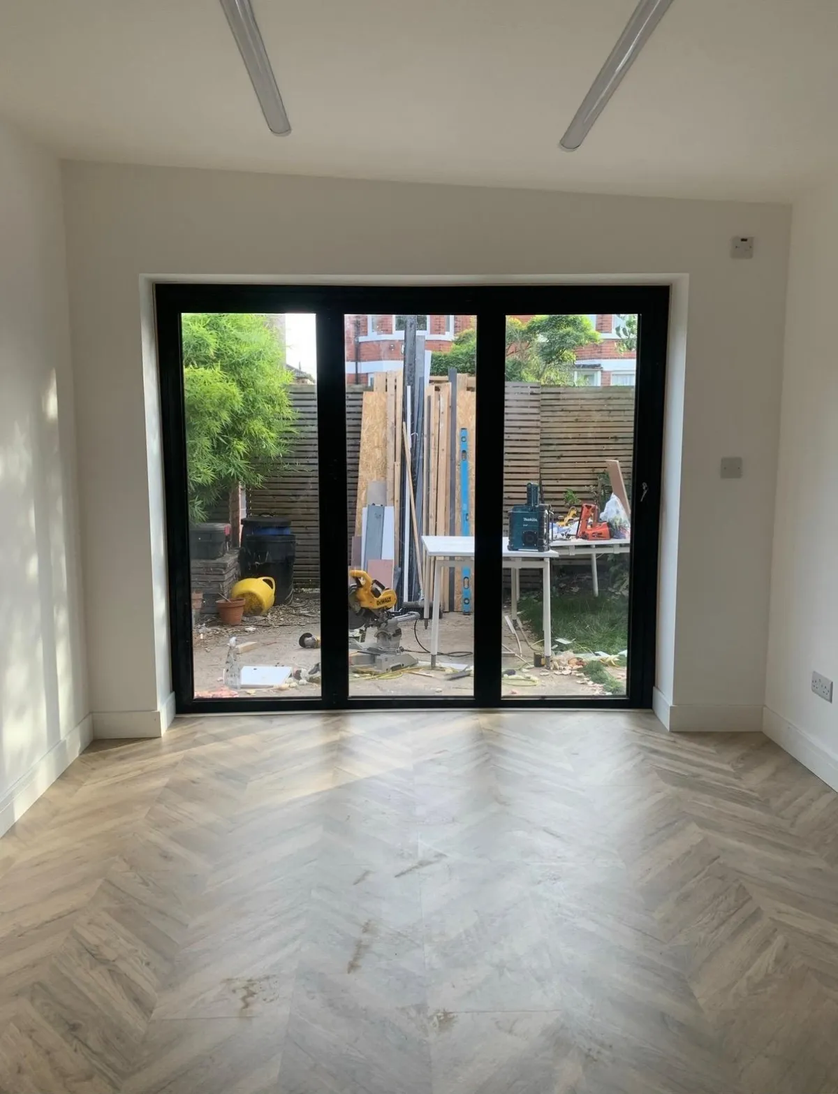 Finished garden room interior with herringbone floor and black-framed sliding doors