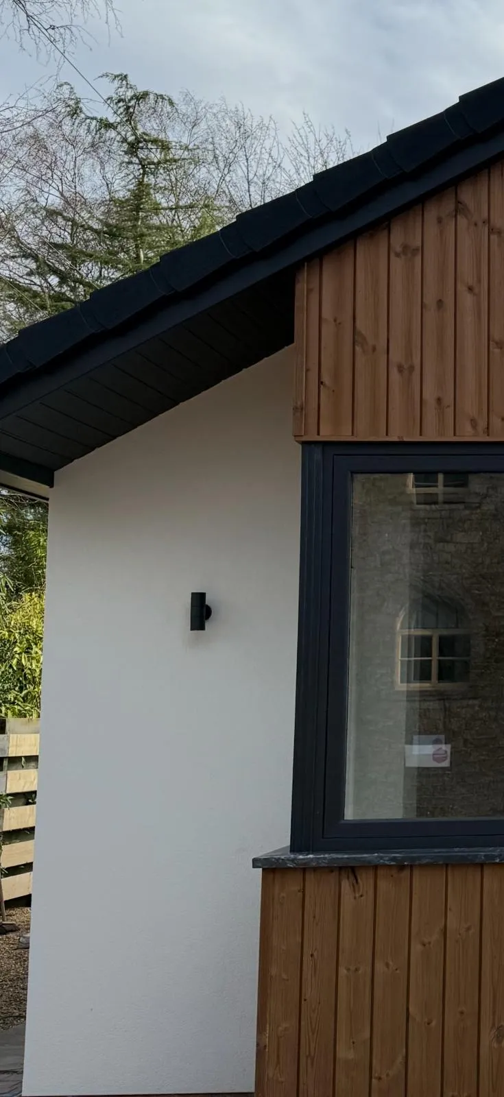 Finished garden room exterior with pitched roof, timber cladding and white render