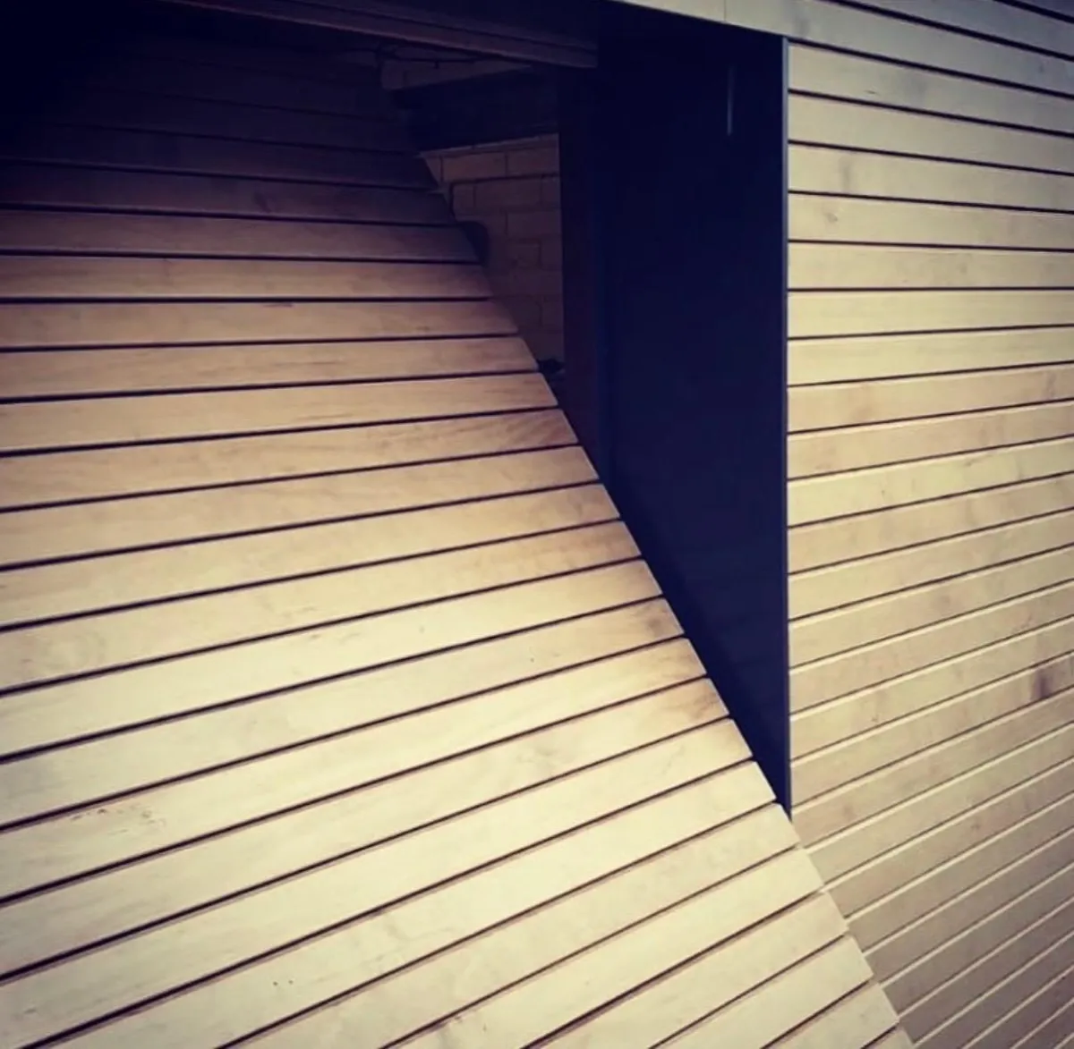 Horizontal timber cladding detail with dark corner trim on a garden room