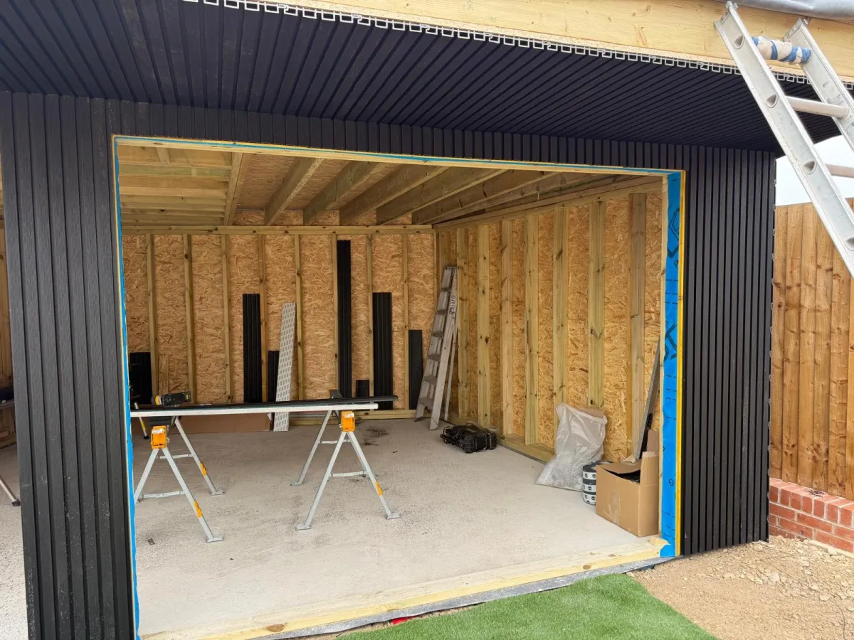 Large garden room build with dark cladding and open front during construction