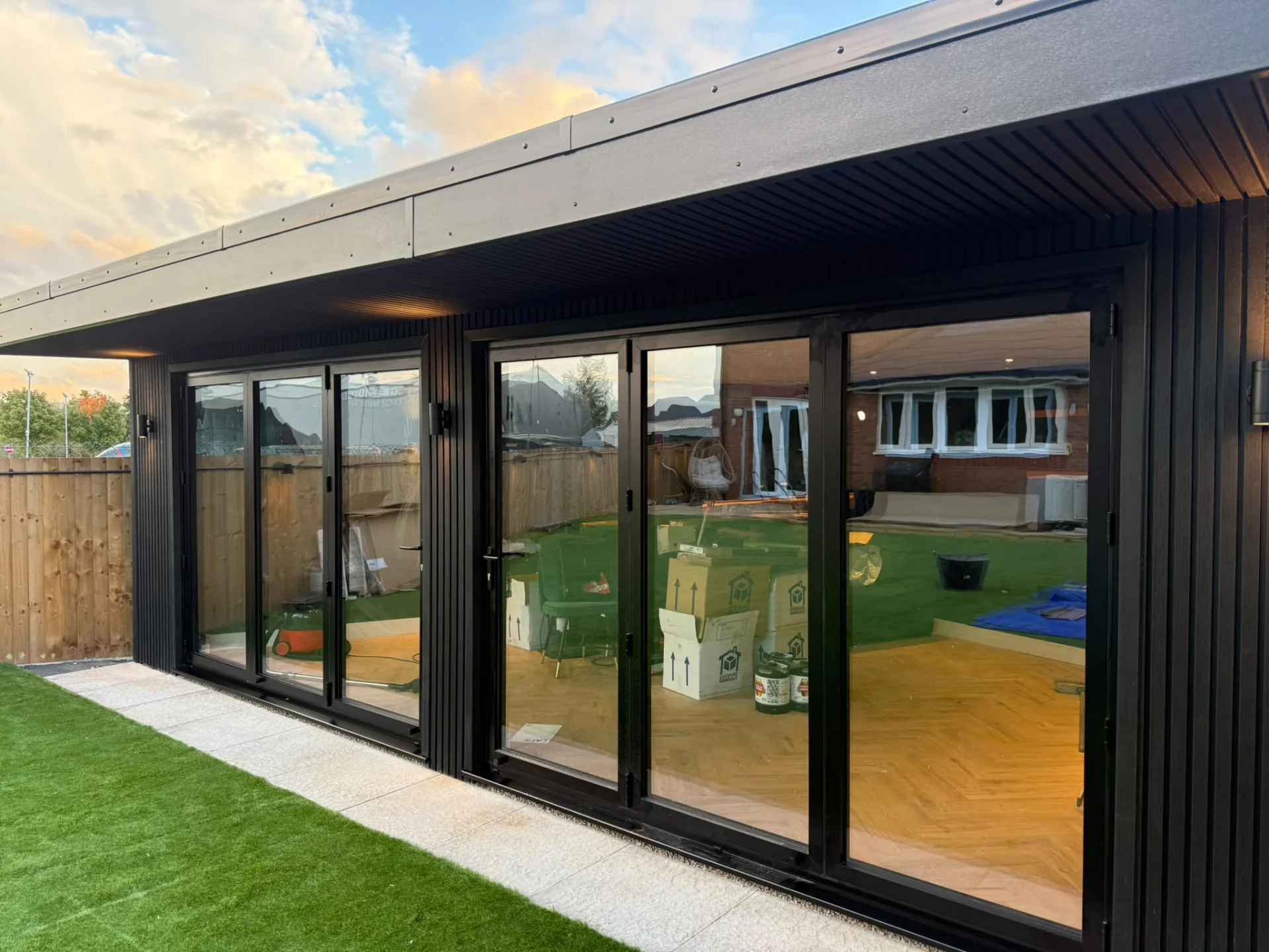 Close view of black-framed garden room doors, vertical cladding and roof overhang
