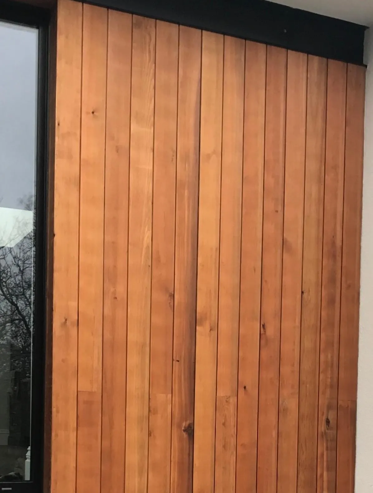 Vertical timber cladding beside a dark-framed window on a finished garden room